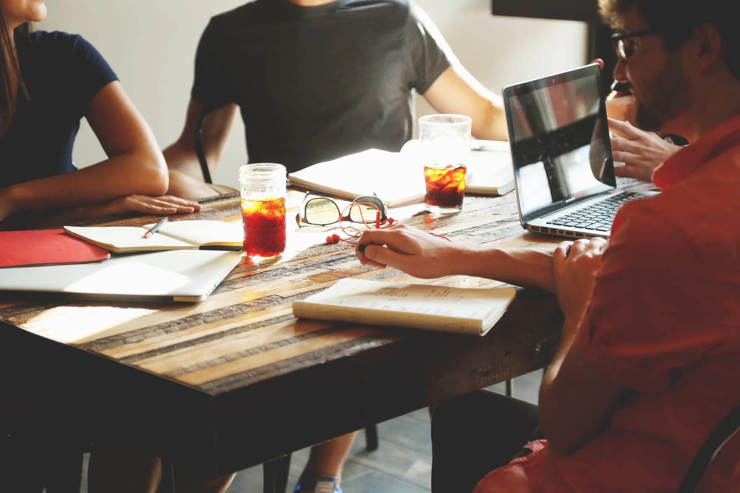 A small team working through a project together around a table with laptops and notebooks